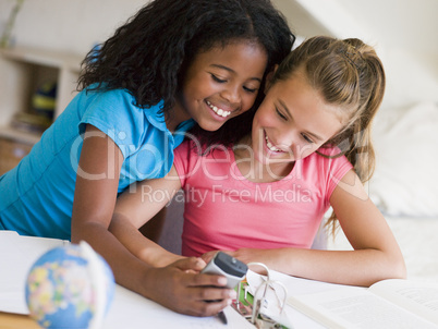 Young Girls Distracted From Their Homework, Playing With A Cellp