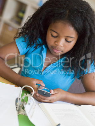 Young Girl Distracted From Her Homework, Playing With A Cellphon