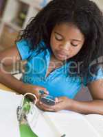 Young Girl Distracted From Her Homework, Playing With A Cellphon