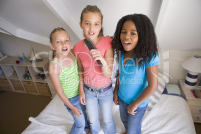 Three Young Girls Standing On A Bed, Singing Into A Hairbrush