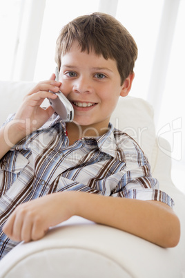 Young Boy Sitting On A Sofa Talking On A Mobile Phone