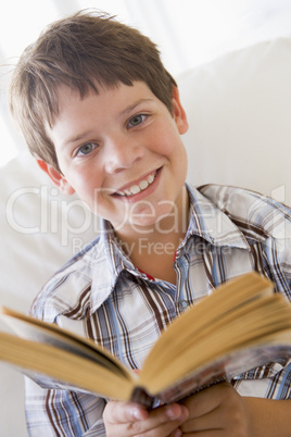 Young Boy Sitting On A Sofa Reading A Book