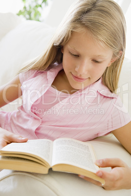 Young Girl Sitting On A Sofa Reading A Book