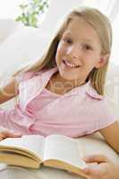 Young Girl Sitting On A Sofa Reading A Book