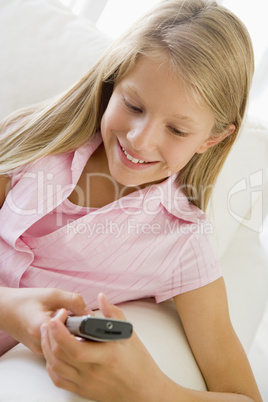 Young Girl Sitting On A Sofa Texting On A Cellphone