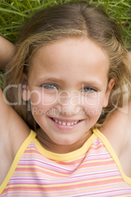 Young Girl Lying Down On The Grass