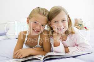 Two Young Girls In Their Pajamas, Reading A Book