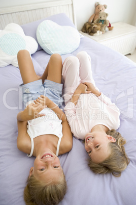 Two Young Girls In Their Pajamas Lying On A Bed