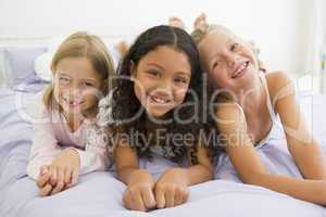 Three Young Girls Lying On A Bed In Their Pajamas