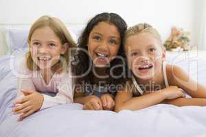 Three Young Girls Lying On A Bed In Their Pajamas