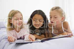 Three Young Girls Lying On A Bed In Their Pajamas