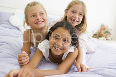 Three Young Girls Lying On Top Of Each Other In Their Pajamas