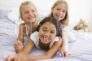 Three Young Girls Lying On Top Of Each Other In Their Pajamas