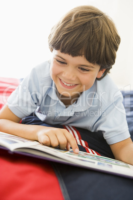 Young Boy Lying Down On His Bed Reading A Book