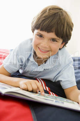 Young Boy Lying Down On His Bed Reading A Book