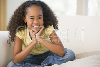 Young Girl Sitting Cross Legged On A Sofa At Home