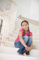 Young Girl Sitting On A Stairwell At Home