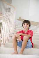 Young Boy Sitting On A Stairwell At Home