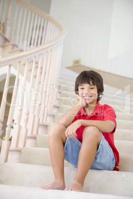 Young Boy Sitting On A Stairwell At Home