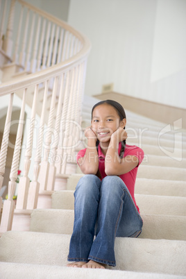 Young Girl Sitting On A Stairwell At Home