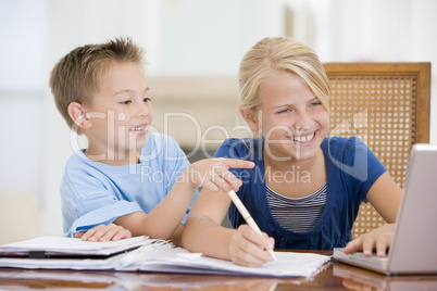 Boy Pointing At Big Sisters Homework On Laptop