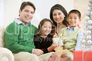 Family Sitting On Sofa Together,Holding A Christmas Gift