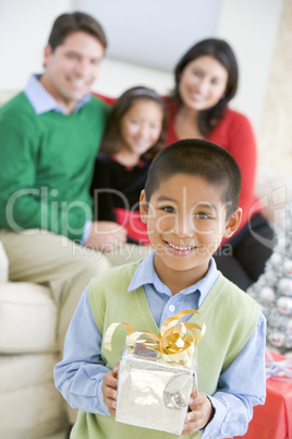 Young Boy Standing Holding Christmas Present,With His Parents An