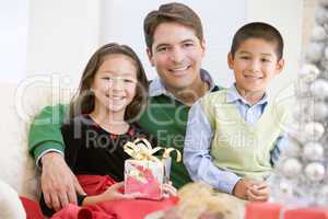 Father And His Son And Daughter Sitting On Sofa,Holding A Christ