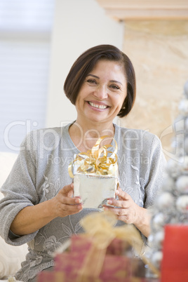Woman Sitting On Sofa Holding A Christmas Gift