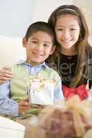 Brother And Sister Sitting On Couch Holding Christmas Gift