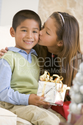 Sister Giving Her Brother A Christmas Present And Kissing Him On