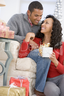 Husband And Wife Affectionately Exchanging Christmas Gifts