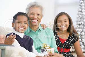 Grandmother Sitting With Her Two Grandchildren,Holding A Christm