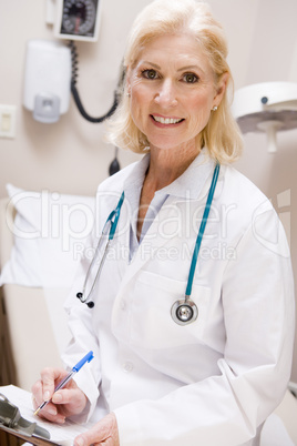 Middle Aged Female Doctor Writing On A Clipboard