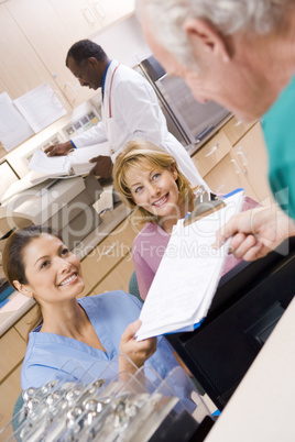 Nurses Being Handed A Clipboard At The Reception Area In A Hospi