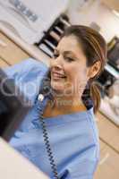 A Nurse On The Telephone At The Reception Area In A Hospital