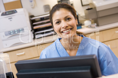 A Nurse Sitting At A Computer At The Reception Area Of A Hospita