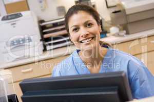 A Nurse Sitting At A Computer At The Reception Area Of A Hospita