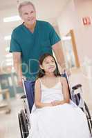 An Orderly Pushing A Little Girl In A Wheelchair Down A Hospital