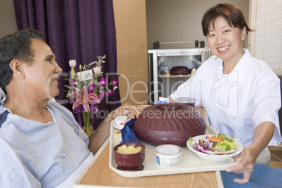 Nurse Serving A Patient A Meal In His Bed