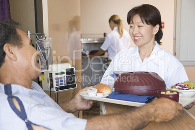 Nurse Serving A Patient A Meal In His Bed