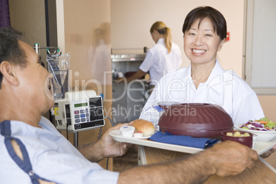 Nurse Serving A Patient A Meal In His Bed