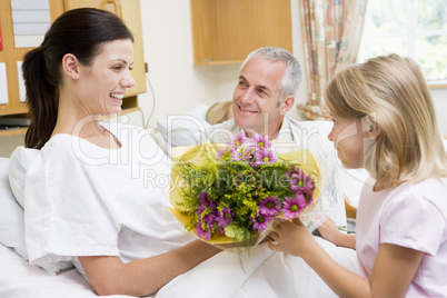 Young Girl Giving Flowers To Her Mother In Hospital