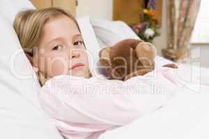 Young Girl Lying In Hospital Bed With Teddy Bear