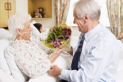 Senior Man Giving Flowers To His Wife In Hospital