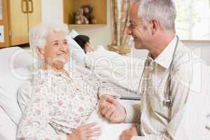 Doctor Sitting With Senior Woman In Hospital