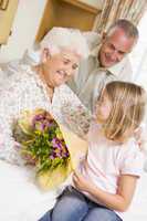 Granddaughter Giving Flowers To Her Grandmother In Hospital
