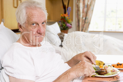 Senior Man Eating Hospital Food In Bed