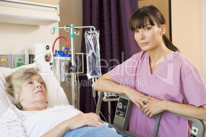 Nurse Checking Up On Patient Lying In Hospital Bed