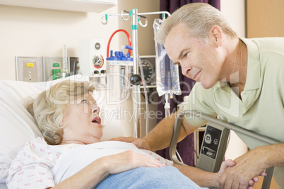 Middle Aged Man Talking To Senior Woman In Hospital